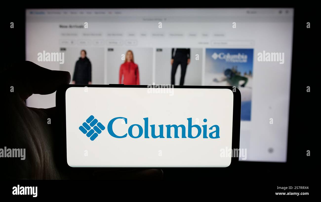 Dans cette illustration photo, une personne tient un téléphone portable avec le logo de l'entreprise américaine Columbia Sportswear Company sur l'écran devant la page Web de l'entreprise. Banque D'Images