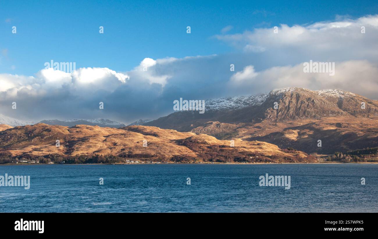 Une vue panoramique d'un loch écossais (probablement dans les Highlands) par une journée partiellement nuageuse. L'image montre des collines et des montagnes vallonnées, certaines avec des parcelles de Banque D'Images