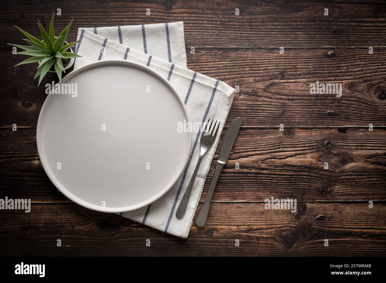 Vue de dessus de la plaque blanche en céramique vide, fourchette et couteau de table sur la table en bois Banque D'Images