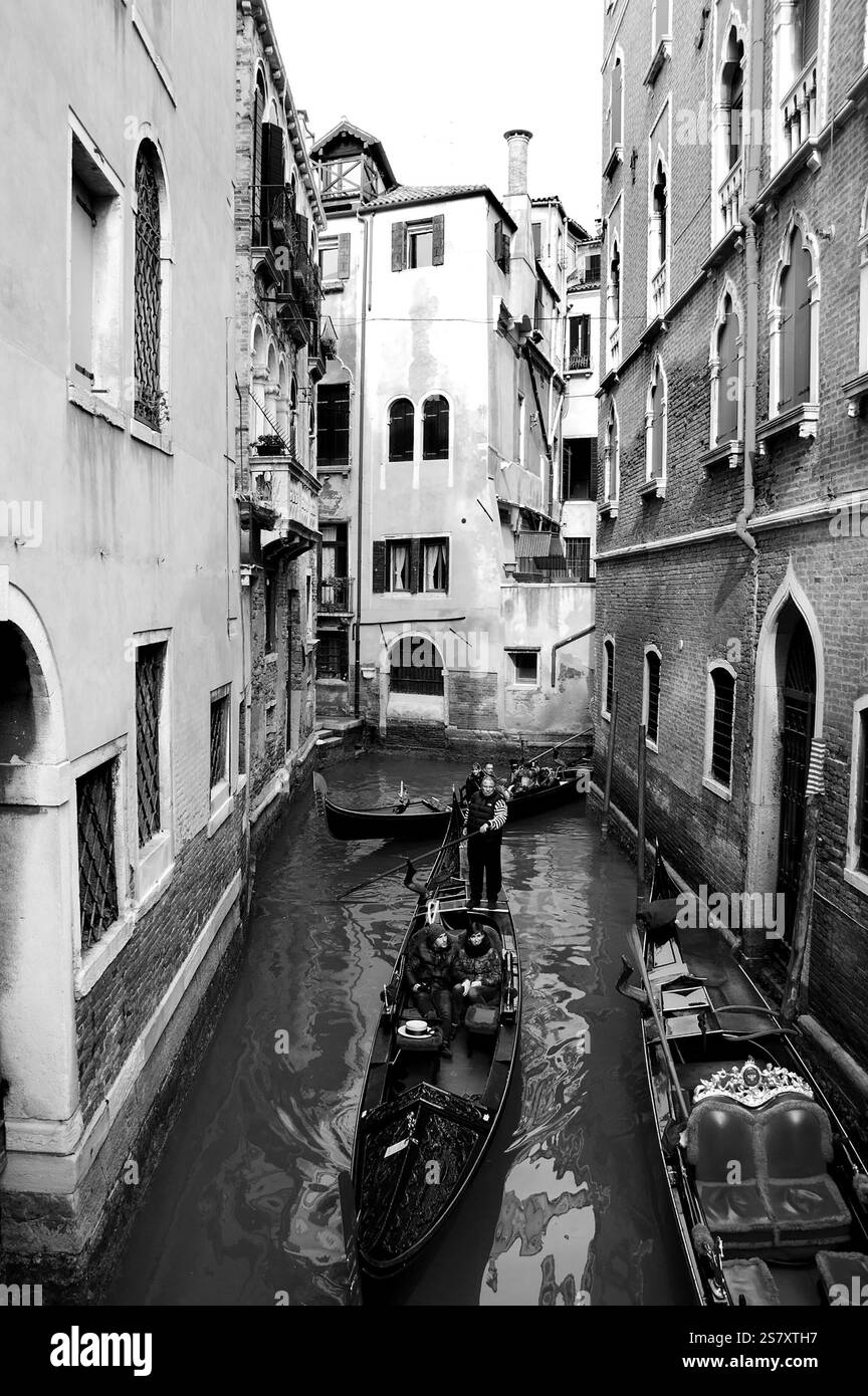 VENISE, ITALIE - 14 FÉVRIER 2015 : trafic de télécabines très fréquenté sur les canaux étroits le jour de la Saint-Valentin pendant le carnaval. Photo historique noir et blanc Banque D'Images