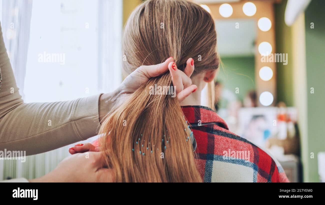 Coiffeur professionnel style queue de cheval élégant pour client blond dans un salon moderne et bien éclairé avec des surfaces réfléchissantes Banque D'Images