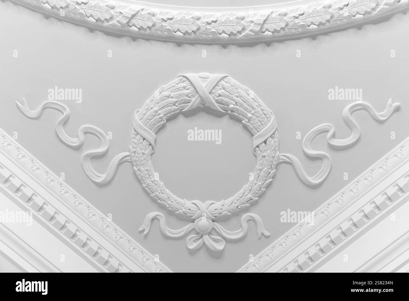 Détails de bas-relief de gypse blanc, conception de coin de plafond avec une couronne avec des rubans, modèle abstrait d'architecture classique Banque D'Images