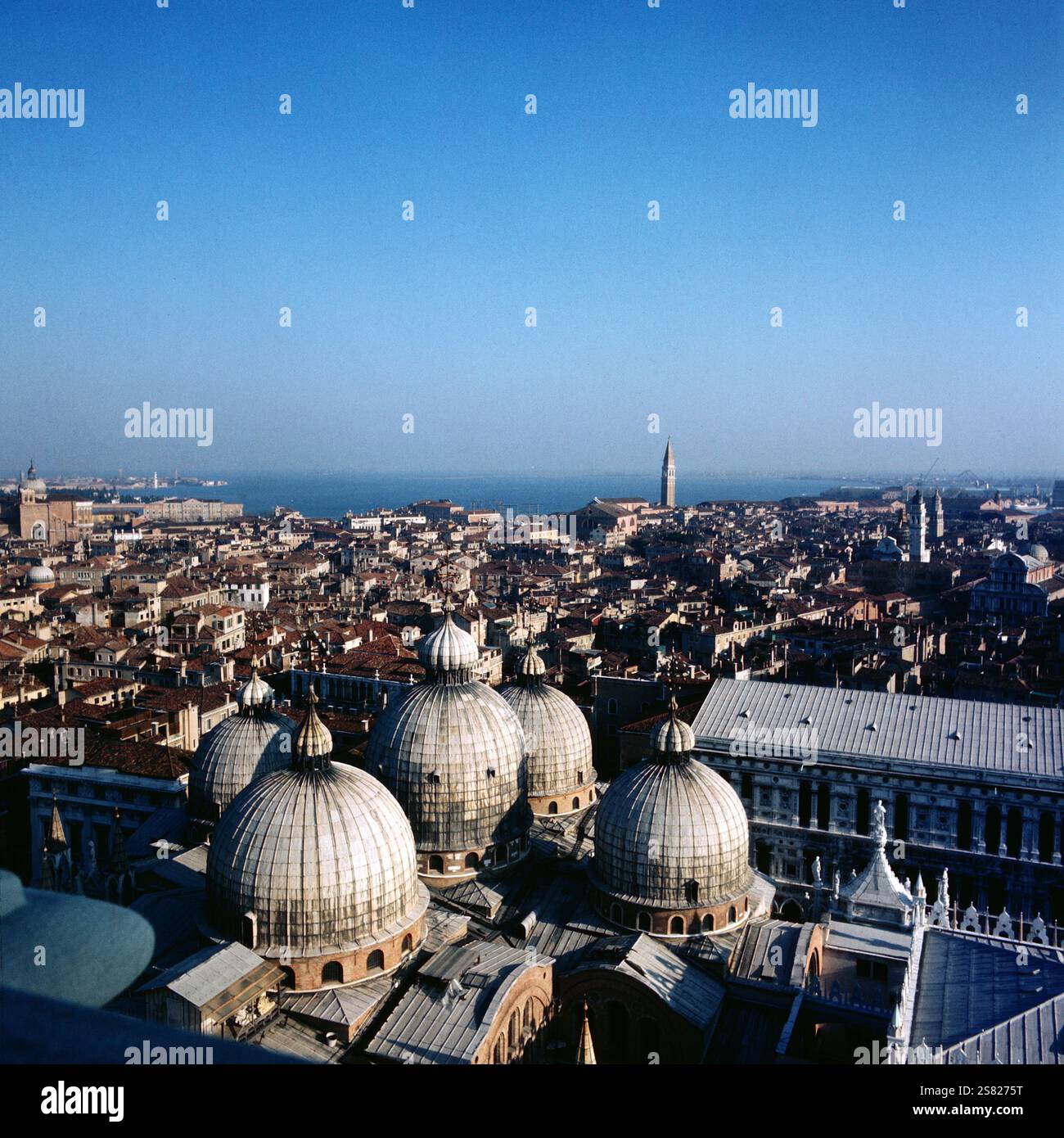 Luftaufnahme von Venedig mit den markanten Kuppeln des Markusdoms und der venezianischen lagune, die sich unter einem klaren blauen Himmel erstreckt, Italien um 1976. Banque D'Images
