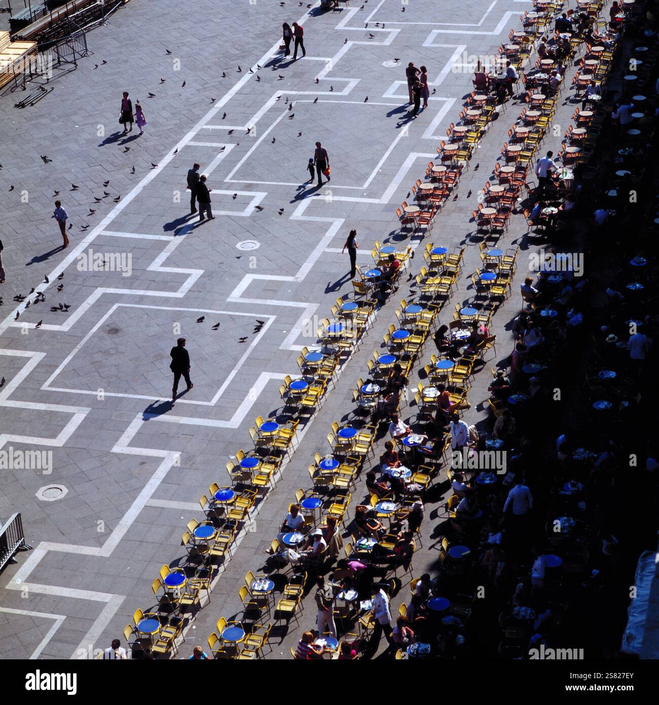 Menschen genießen den sonnigen Tag auf dem Markusplatz in Venedig, Italien, mit Tauben, die auf einem geometry trischen Bürgersteig laufen, Italien um 1976. Banque D'Images