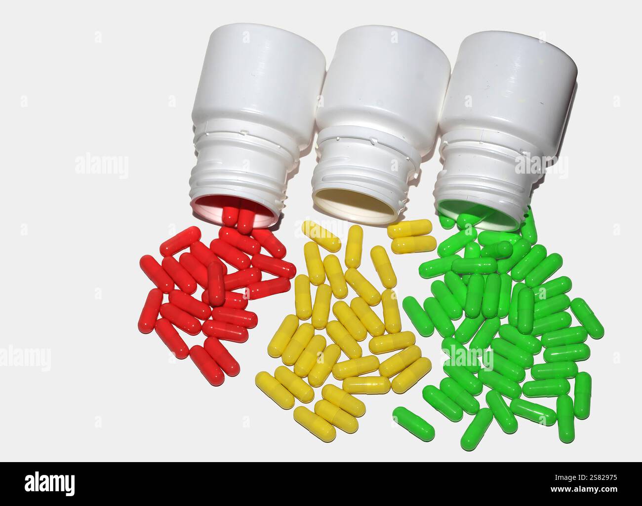 Capsules colorées renversées à partir de trois bouteilles. Une image vibrante présentant des médicaments ou des suppléments. Banque D'Images