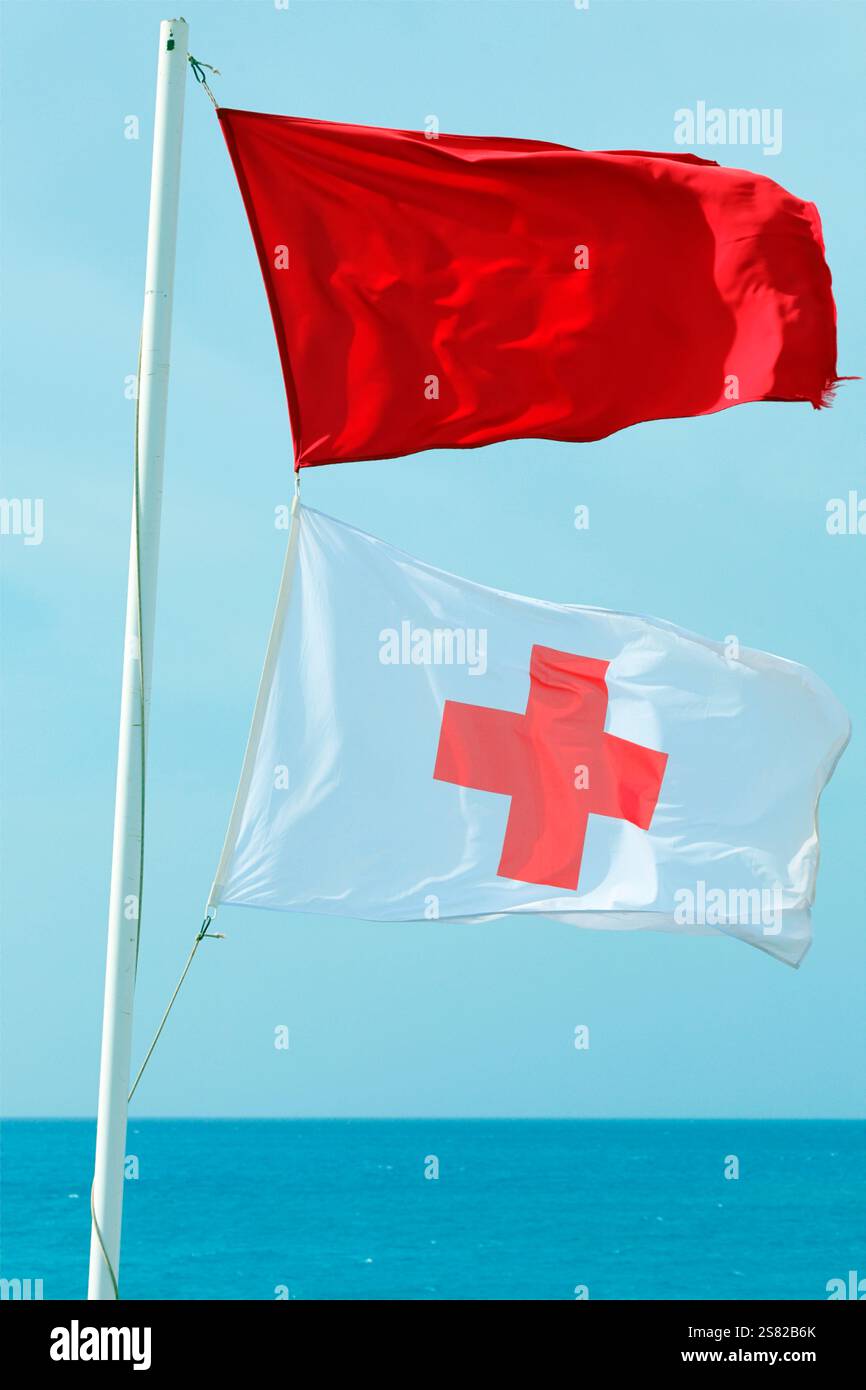 Drapeaux de garde-nageur (cruz roja) flottant sur la plage de Piedra Playa, El Cotillo, Fuerteventura. Prise en décembre 2024. Banque D'Images