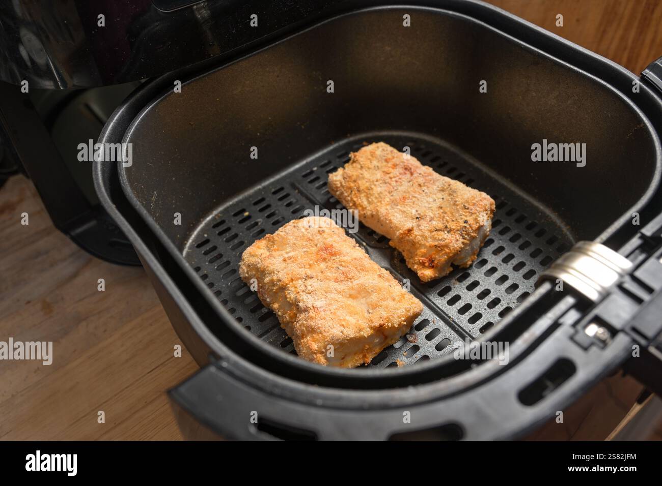 Les filets de poisson panés de morue sont préparés avec une faible teneur en matières grasses dans la friteuse à air chaud, une cuisson saine pour un régime amincissant, une mise au point sélectionnée, une profondeur de champ étroite Banque D'Images