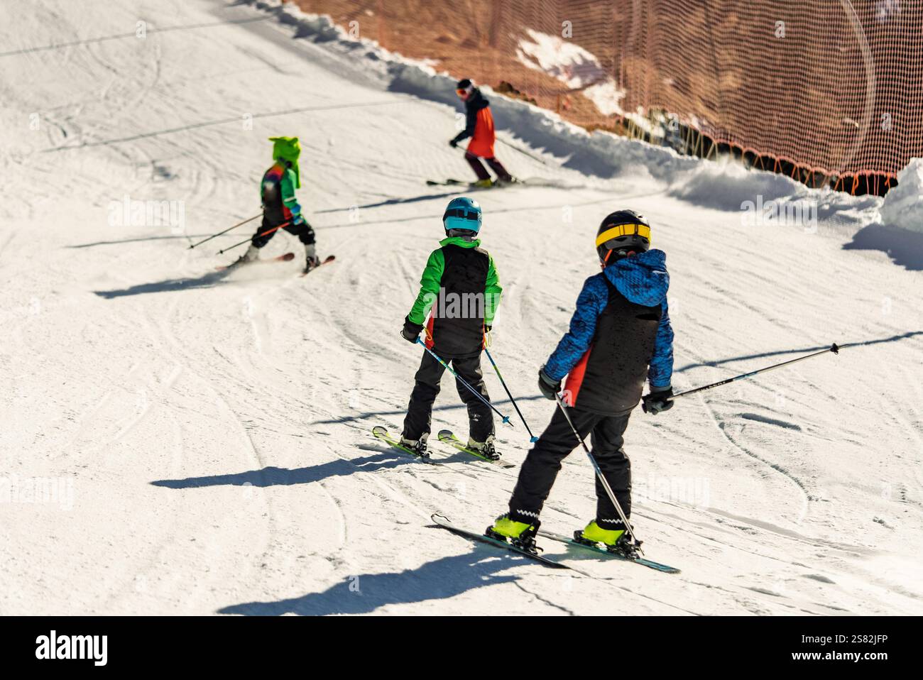 Groupe de personnes skiant dans les montagnes par une journée ensoleillée d'hiver. Cours de ski avec instructeurs locaux. Les enfants apprennent à skier avec un moniteur. Enfants Banque D'Images
