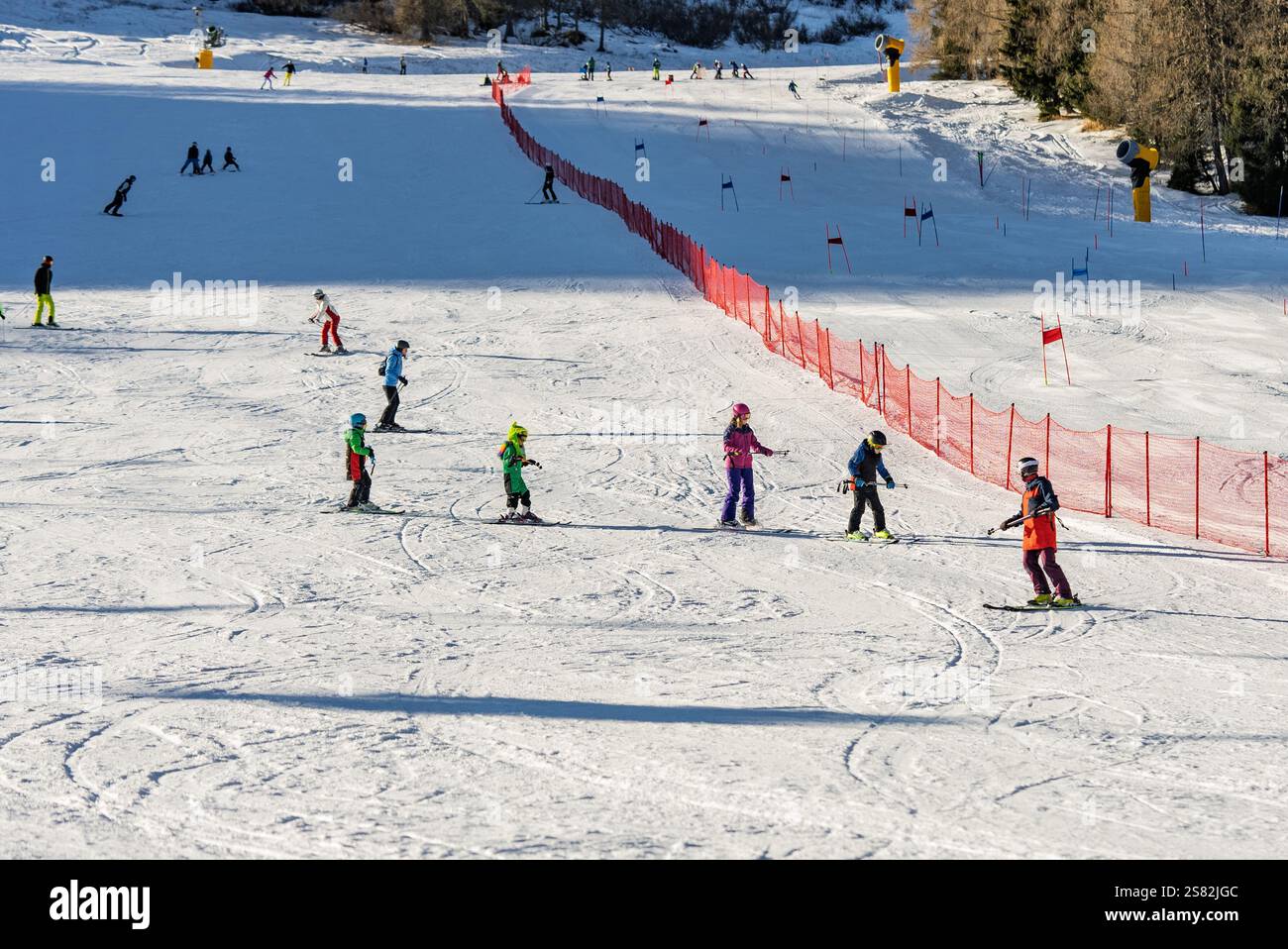 Groupe de personnes skiant dans les montagnes par une journée ensoleillée d'hiver. Cours de ski avec instructeurs locaux. Les enfants apprennent à skier avec un moniteur. Enfants Banque D'Images