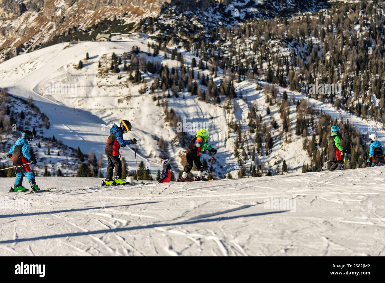 Groupe de personnes skiant dans les montagnes par une journée ensoleillée d'hiver. Cours de ski avec instructeurs locaux. Les enfants apprennent à skier avec un moniteur. Enfants Banque D'Images