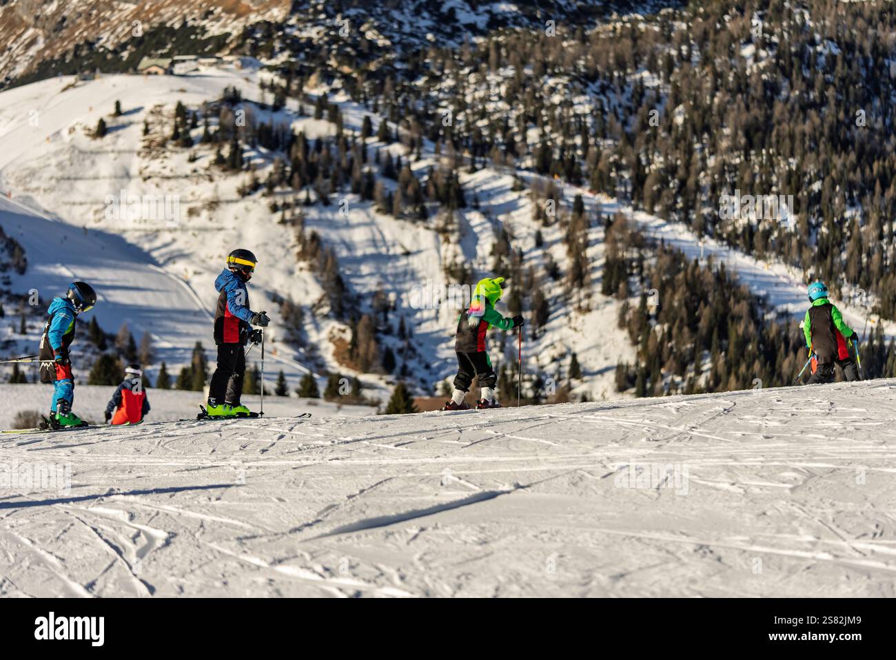 Groupe de personnes skiant dans les montagnes par une journée ensoleillée d'hiver. Cours de ski avec instructeurs locaux. Les enfants apprennent à skier avec un moniteur. Enfants Banque D'Images