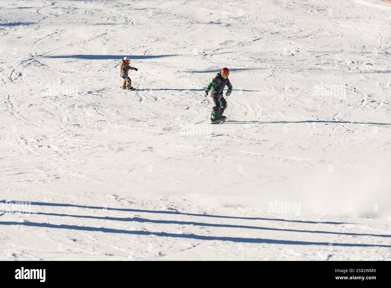 Groupe de personnes snowboard dans les montagnes par une journée ensoleillée d'hiver. Cours de snowboard avec instructeurs locaux. Les enfants apprennent à faire du snowboard avec un instruc Banque D'Images