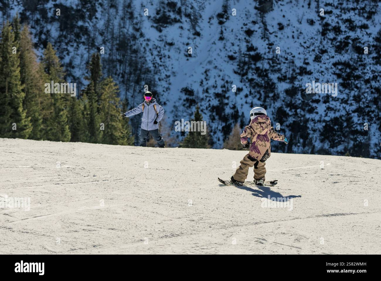 Groupe de personnes snowboard dans les montagnes par une journée ensoleillée d'hiver. Cours de snowboard avec instructeurs locaux. Les enfants apprennent à faire du snowboard avec un instruc Banque D'Images