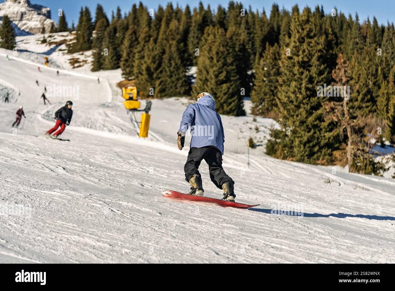 Groupe de personnes snowboard dans les montagnes par une journée ensoleillée d'hiver. Cours de snowboard avec instructeurs locaux. Les enfants apprennent à faire du snowboard avec un instruc Banque D'Images
