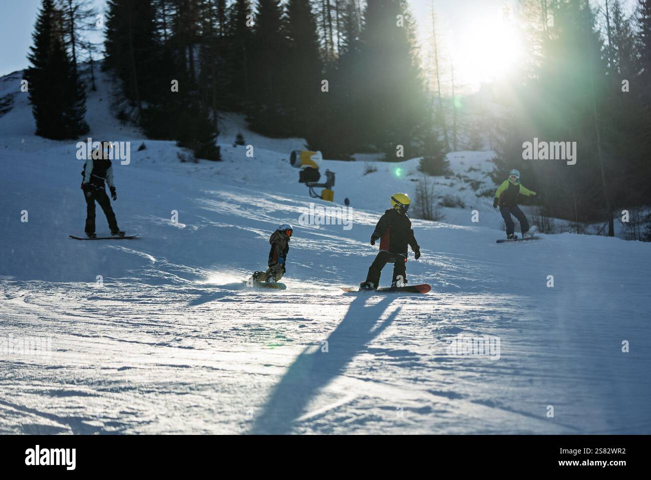 Groupe de personnes snowboard dans les montagnes par une journée ensoleillée d'hiver. Cours de snowboard avec instructeurs locaux. Les enfants apprennent à faire du snowboard avec un instruc Banque D'Images