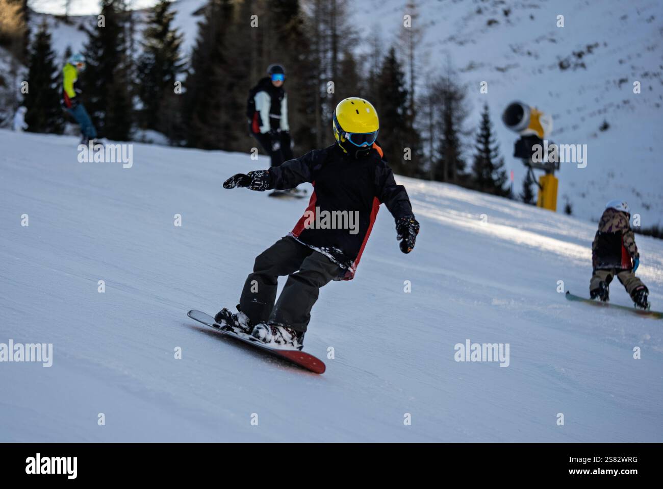 Groupe de personnes snowboard dans les montagnes par une journée ensoleillée d'hiver. Cours de snowboard avec instructeurs locaux. Les enfants apprennent à faire du snowboard avec un instruc Banque D'Images