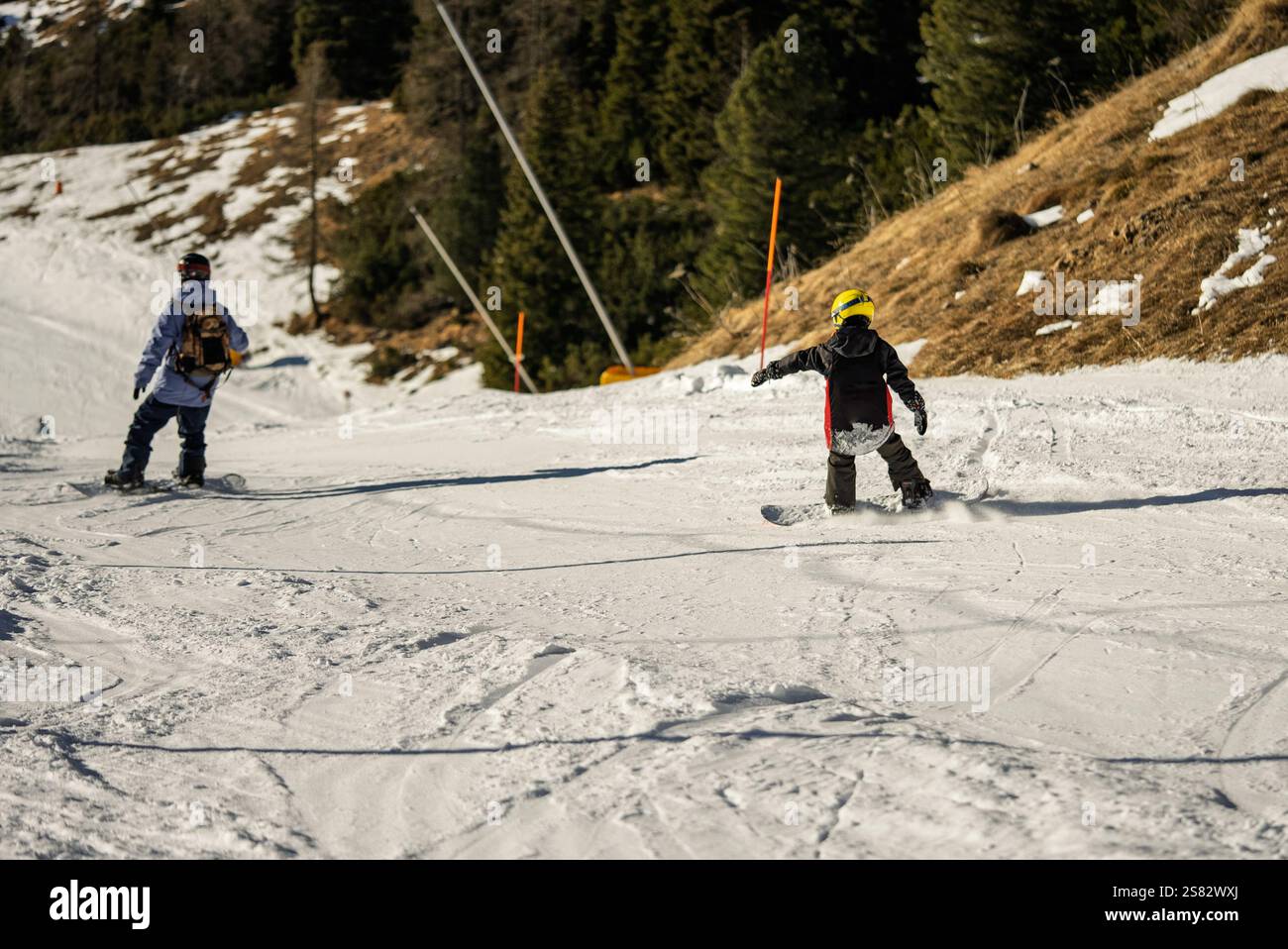 Groupe de personnes snowboard dans les montagnes par une journée ensoleillée d'hiver. Cours de snowboard avec instructeurs locaux. Les enfants apprennent à faire du snowboard avec un instruc Banque D'Images