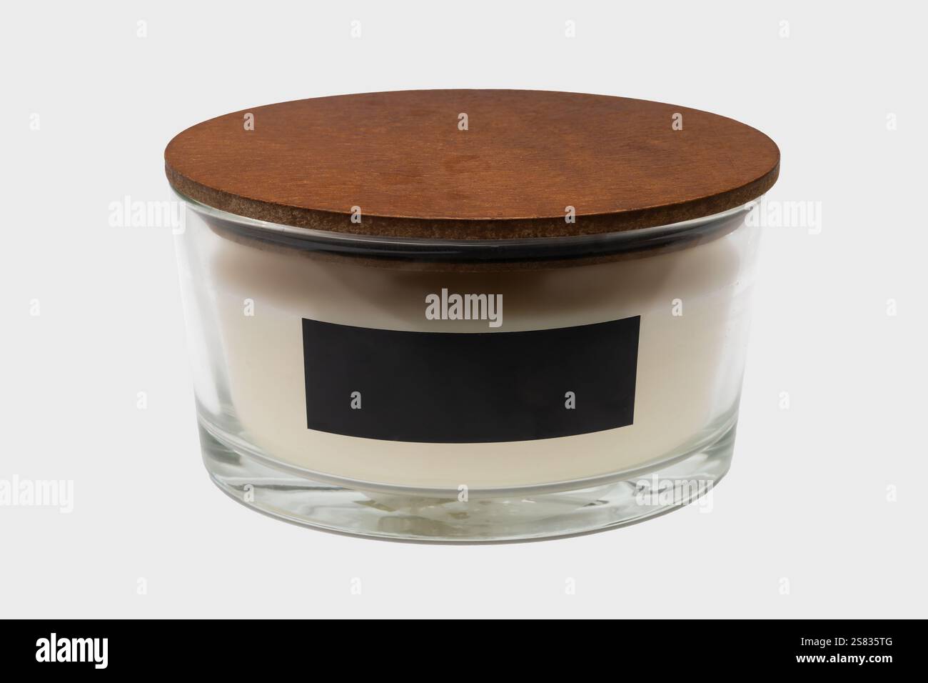 L'image peut être utilisée pour les images de décoration intérieure. Bougie en verre avec capuchon en bois. La bougie est sur un fond transparent. Avec étiquette. Banque D'Images