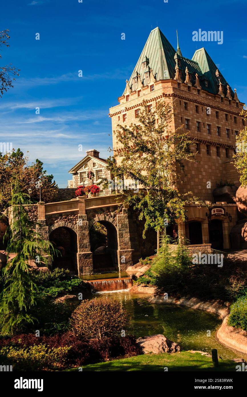 Un grand bâtiment avec un toit vert et une façade en pierre. Le bâtiment est entouré d'arbres et de buissons Banque D'Images