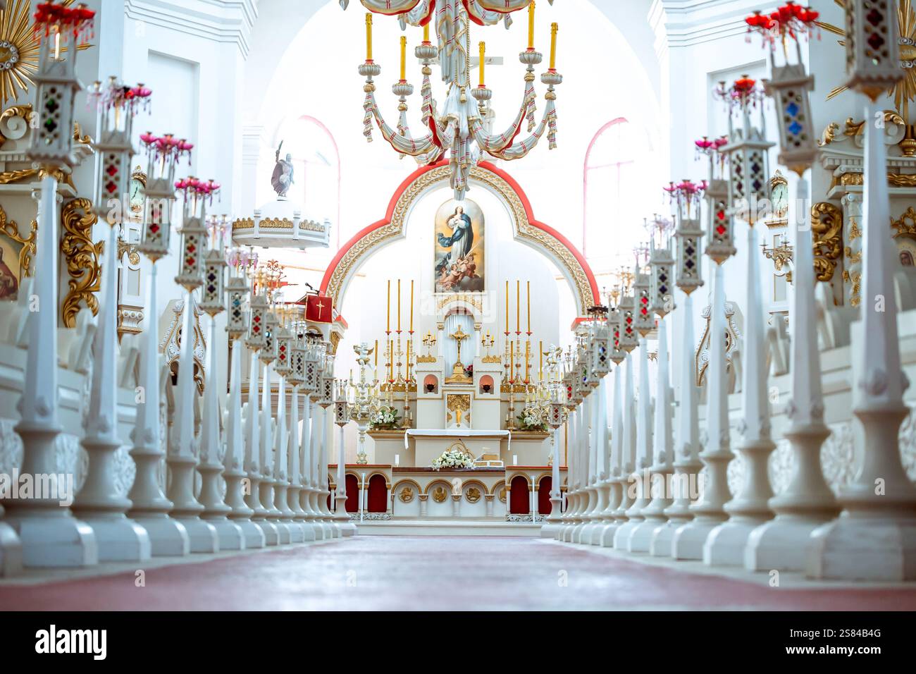 L'intérieur de l'église est richement décoré et comprend un autel doré, des arrangements floraux, des colonnes blanches, des fenêtres cintrées et un grand lustre. Banque D'Images