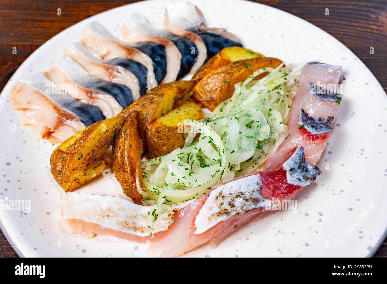 Le poisson fraîchement préparé est habilement disposé sur une assiette avec des pommes de terre grillées et des oignons hachés, mettant en valeur une présentation culinaire vibrante à un Banque D'Images