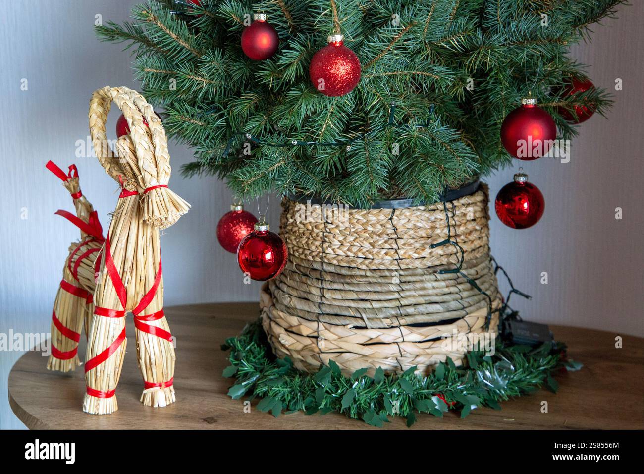 Un présentoir de Noël d'inspiration scandinave avec un arbre artificiel décoré en rouge dans un pot de paille, accompagné d'une chèvre Yule traditionnelle. Banque D'Images