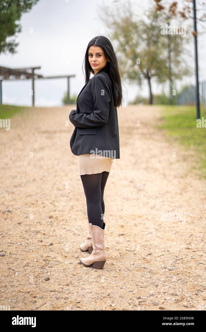 Femme d'affaires marchant dans un chemin de parc portant des bottes de cow-boy, profitant d'une journée de repos relaxante Banque D'Images