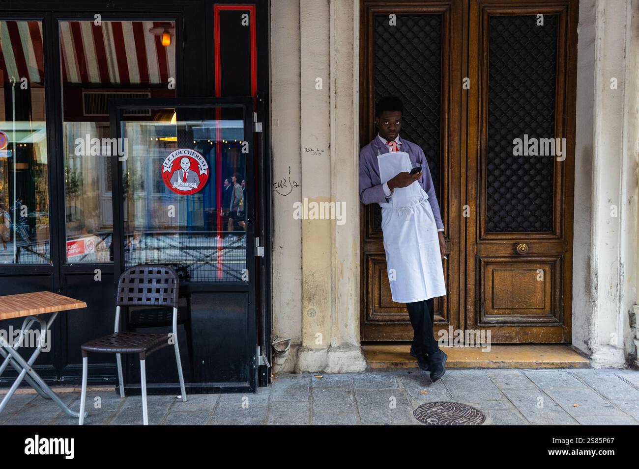 Serveur en pause devant un restaurant à Paris, France Banque D'Images