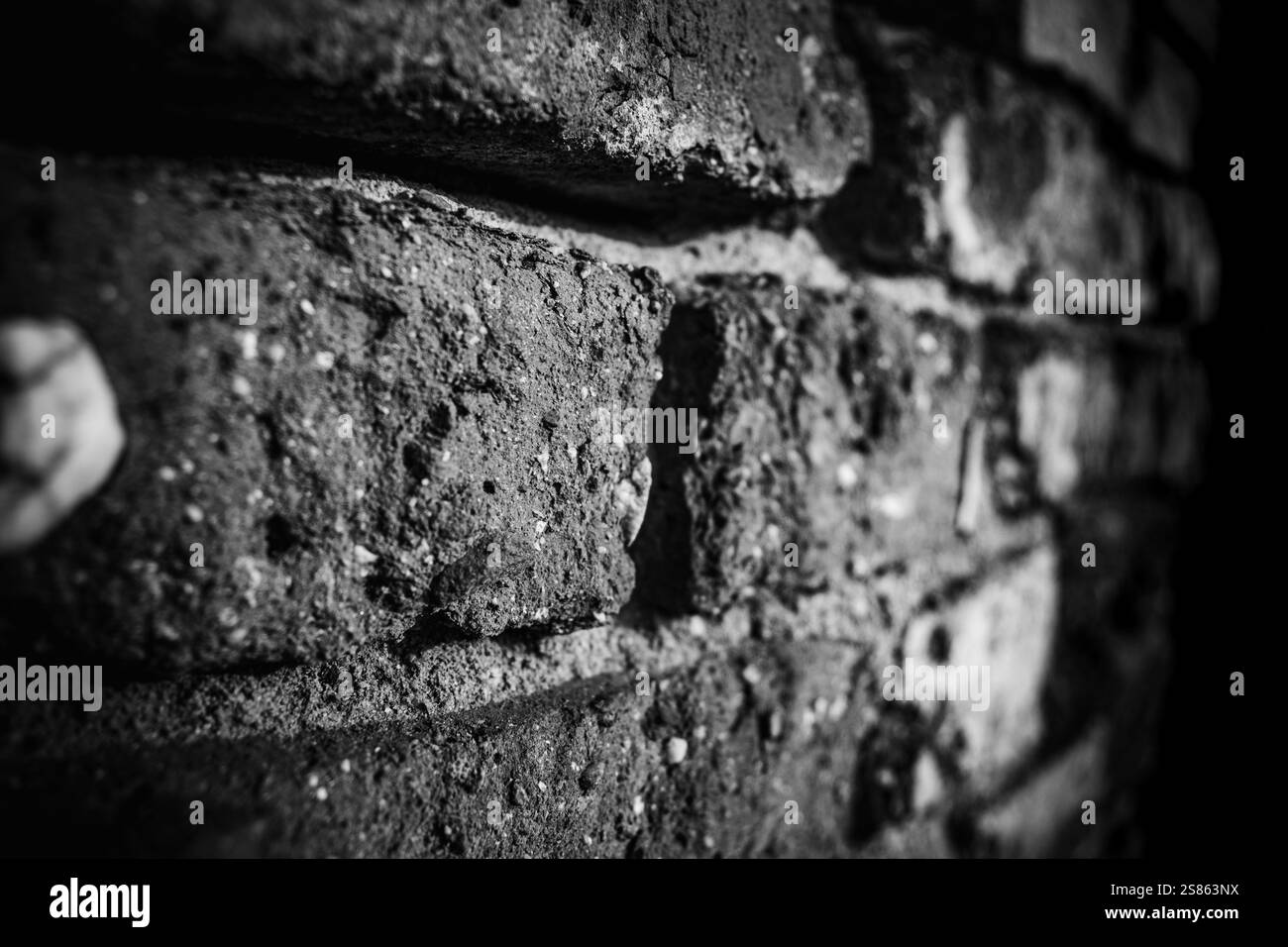 Vue détaillée du mur de briques texturées mettant en évidence les surfaces altérées en photographie monochrome Banque D'Images
