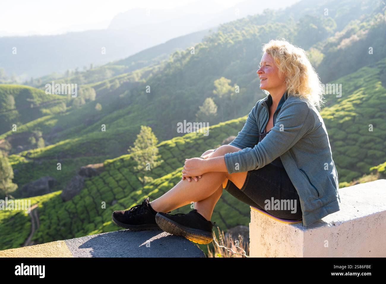Jeune femme européenne jouissant d'une vue panoramique sur les plantations de thé à Munnar. Écotourisme au Kerala, Inde Banque D'Images