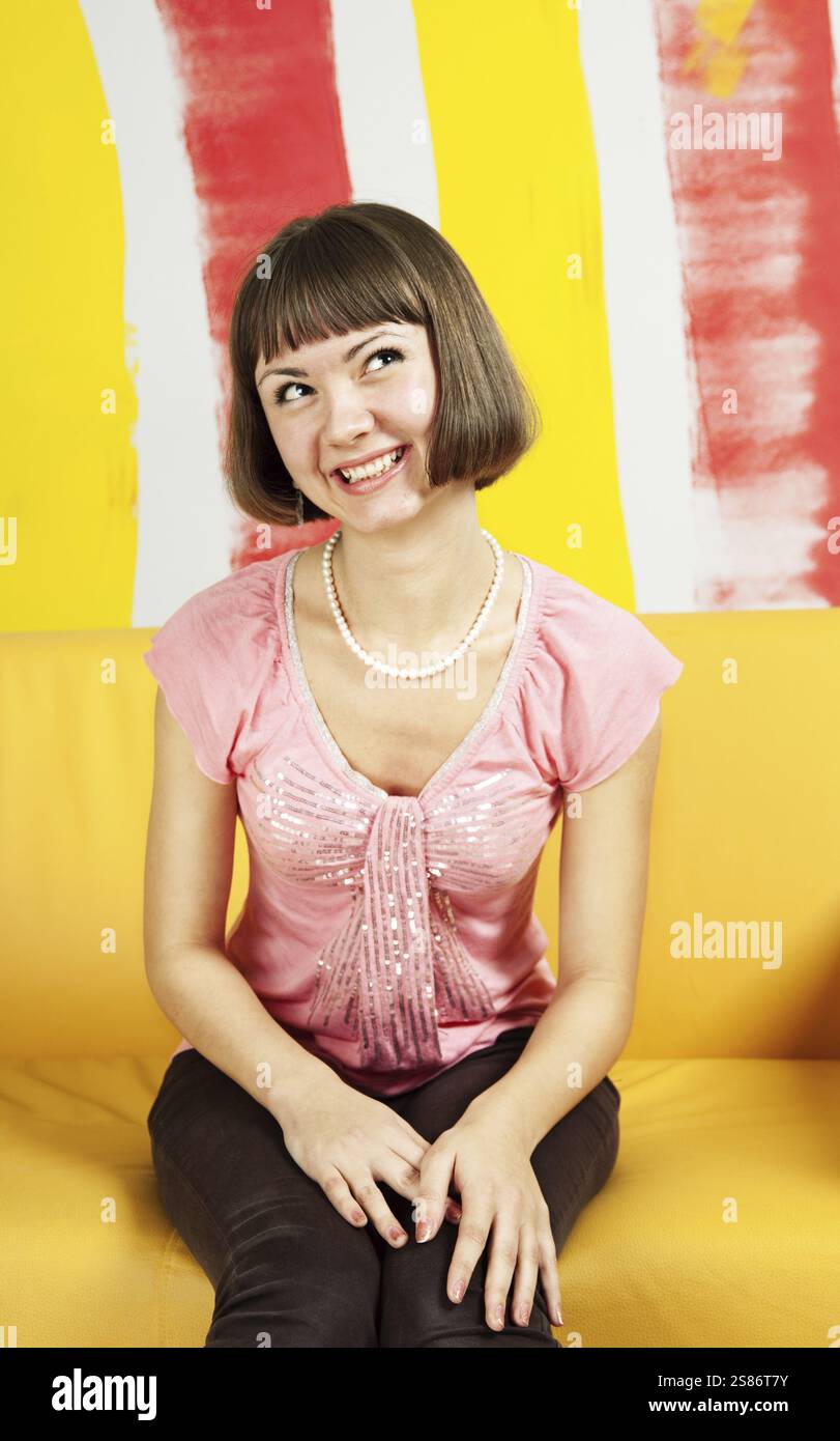 Jolie jeune femme souriante assise dans un environnement très coloré, Fédération de Russie Banque D'Images