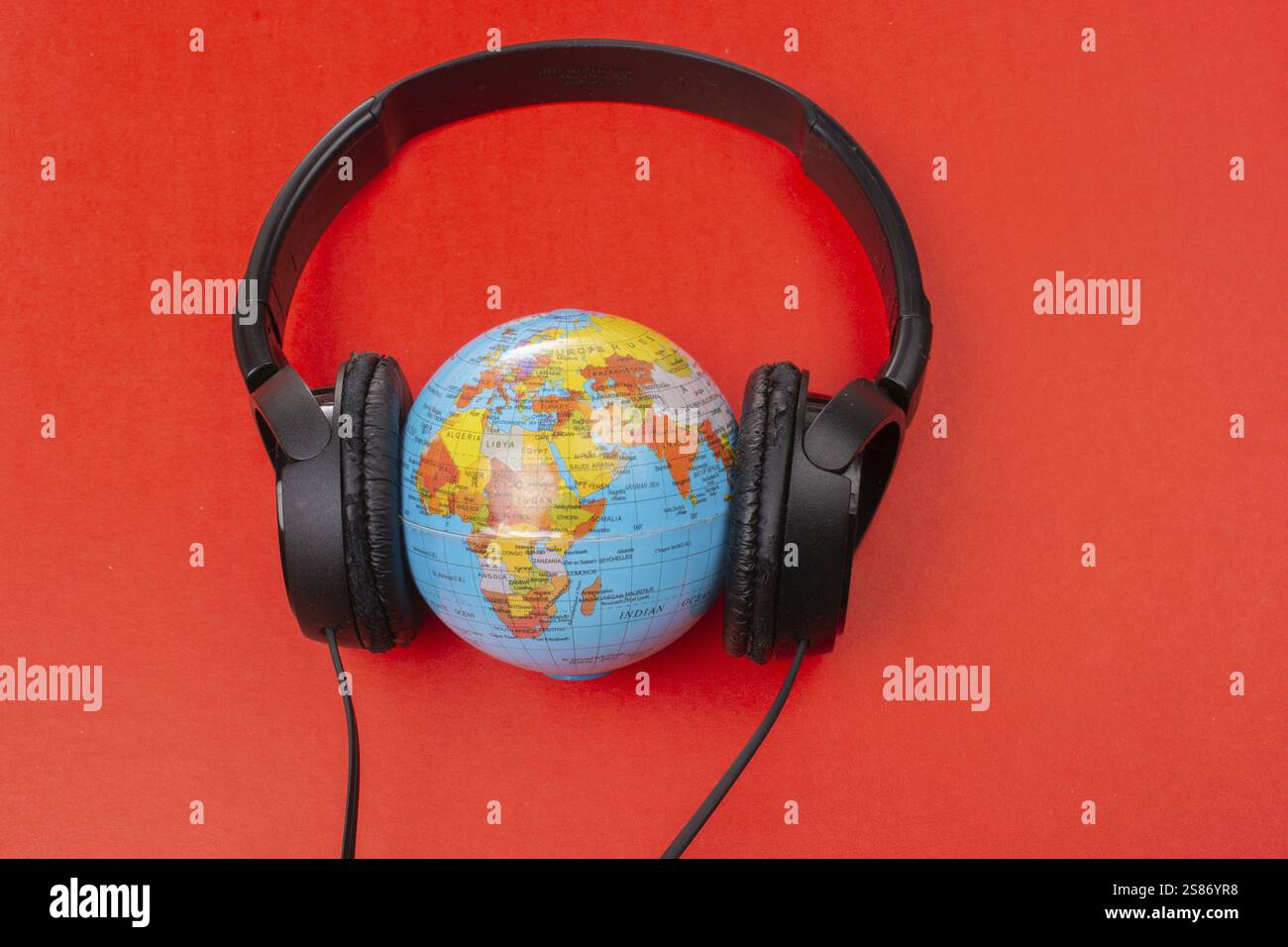 Micro-casque sur globe isolé sur le rouge Banque D'Images