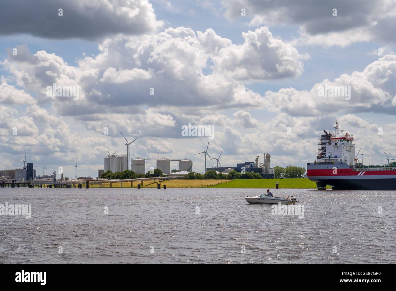 Bateau à moteur dans le port et les usines et les réservoirs de stockage de la grappe chimique Delfzijl le long du canal Sea Harbor, Eemsdelta, Groningen, pays-Bas Banque D'Images