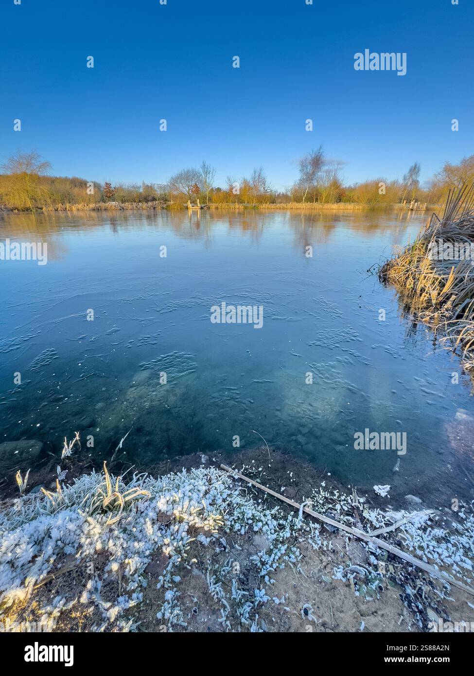 Lac gelé par une journée d'hiver ensoleillée avec un ciel bleu clair. York. ROYAUME-UNI Banque D'Images