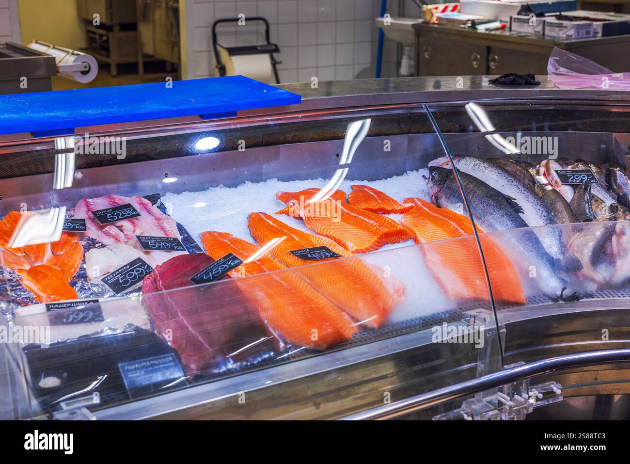 Des filets de saumon frais et du poisson entier sur glace dans les fruits de mer exposés au marché sous des lumières vives. Suède. Banque D'Images