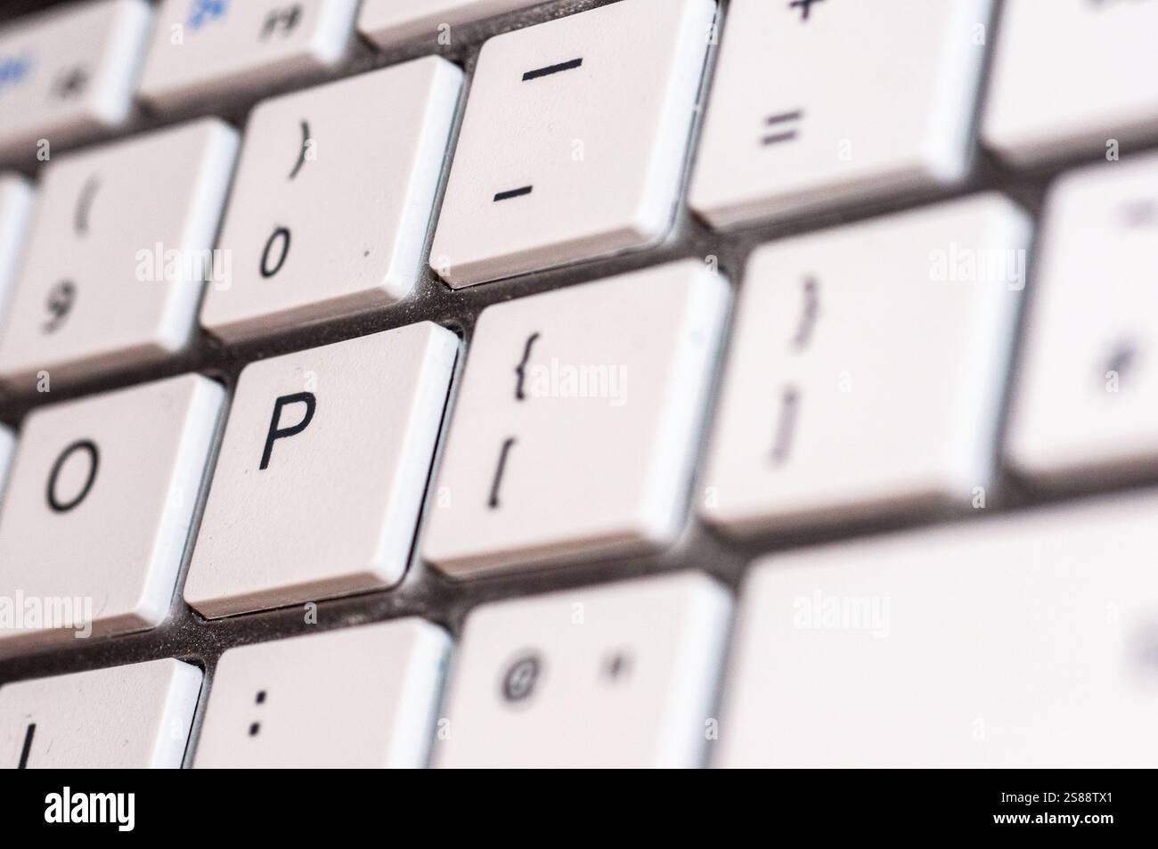 Vue rapprochée d'une section d'un clavier d'ordinateur blanc. L'image montre différentes touches, y compris la lettre 'P', et d'autres caractères comme '0', '=', Banque D'Images