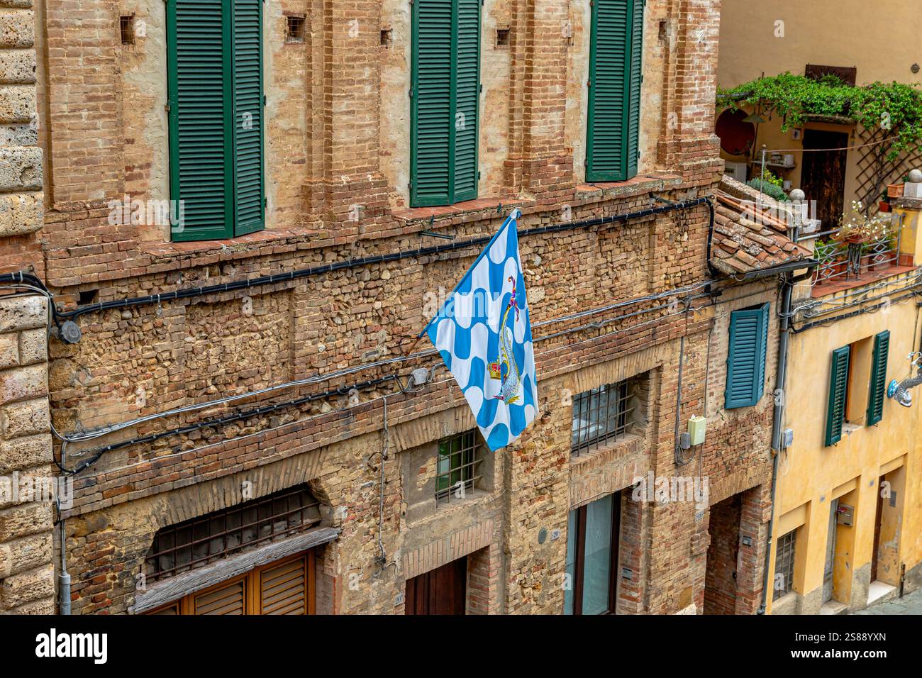 Le drapeau de la Contrada Onda , vague Contrada accroché au mur d'un mur de bâtiment le long de la via Sant'Agata à Sienne , Italie Banque D'Images