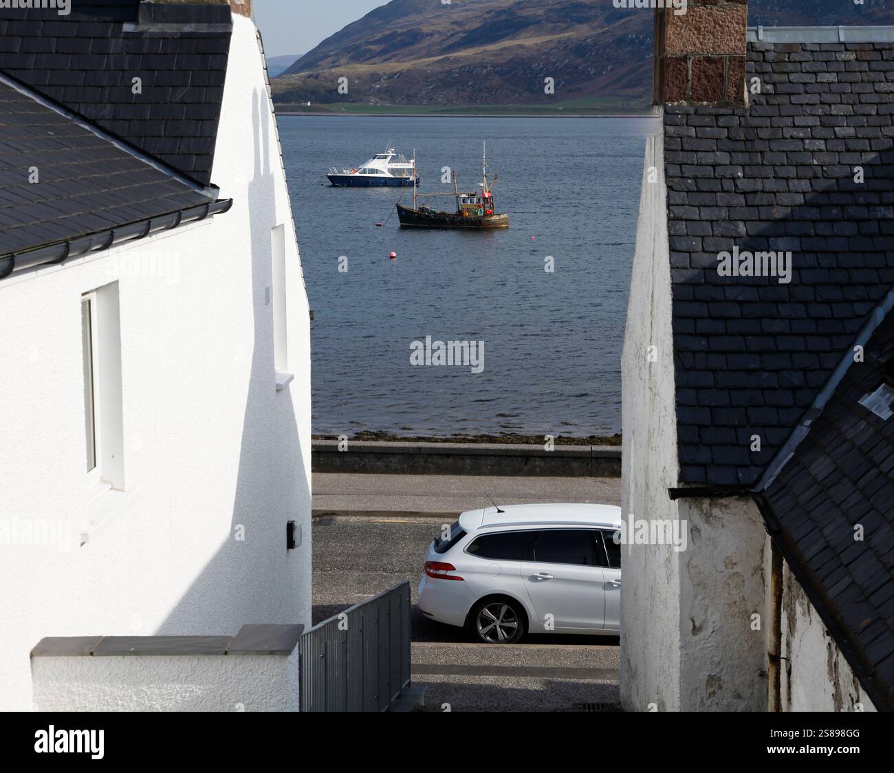 Bateaux à l'ancre sur le Loch Broom vu entre les bâtiments à Ullapool Banque D'Images