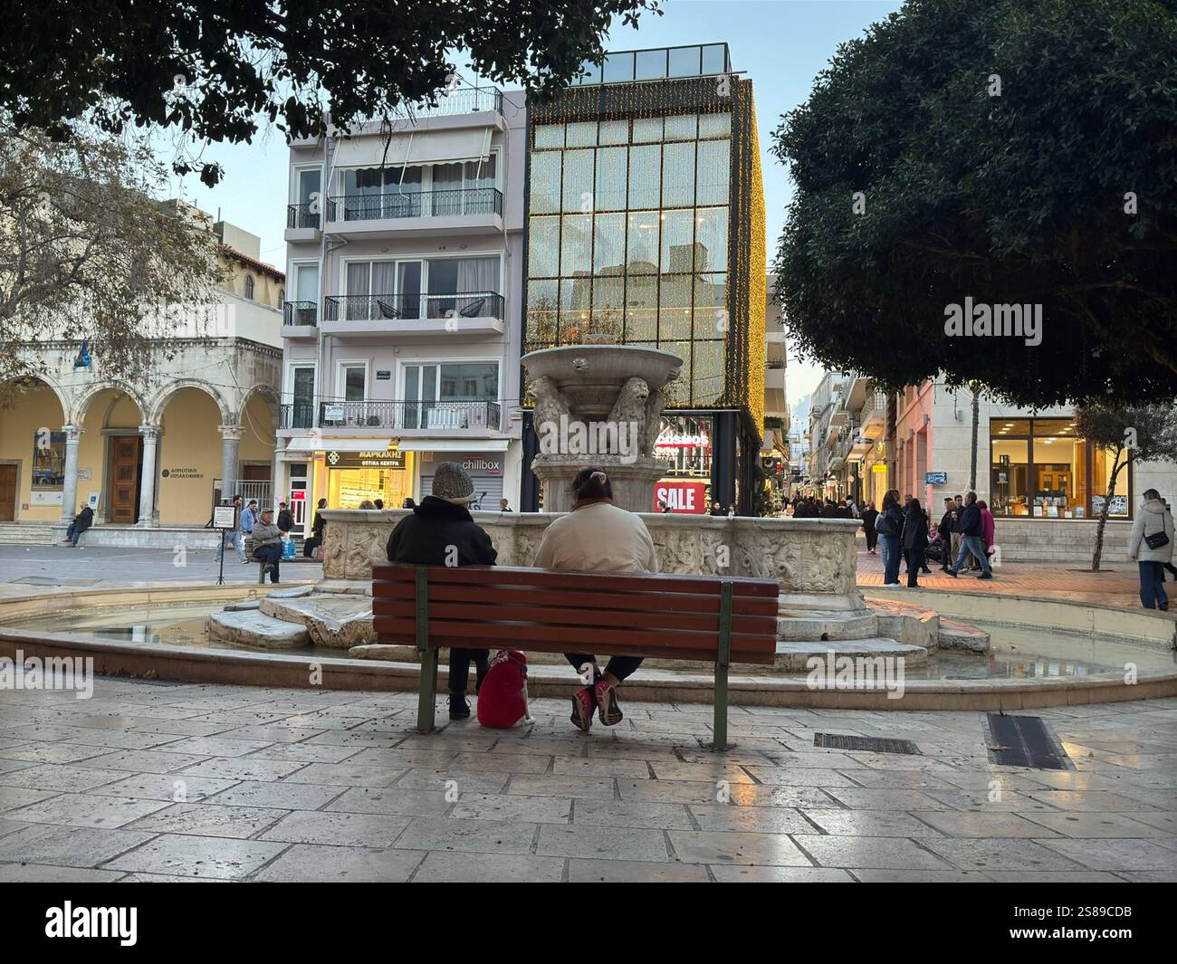 Deux vieilles femmes avec leur chien sont assis sur un banc devant la fontaine Morosini ou Lions à Héraklion pendant la saison des soldes d'hiver Banque D'Images