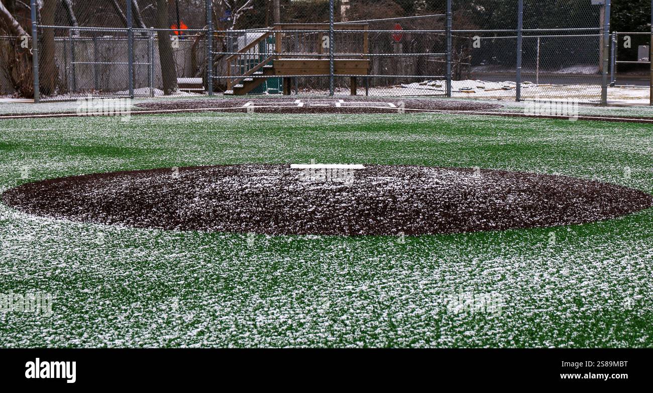 Un terrain de baseball en gazon artificiel immaculé légèrement recouvert de neige, offrant un environnement de jeu frais. Banque D'Images