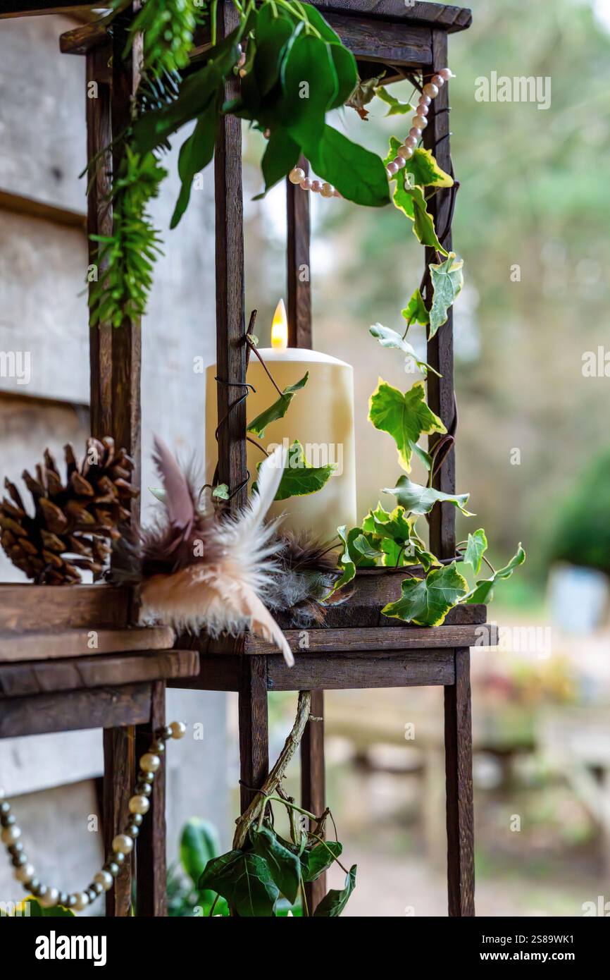 Affichage rustique de bougie avec Ivy, plumes et pomme de pin sur cadre en bois à l'extérieur Banque D'Images