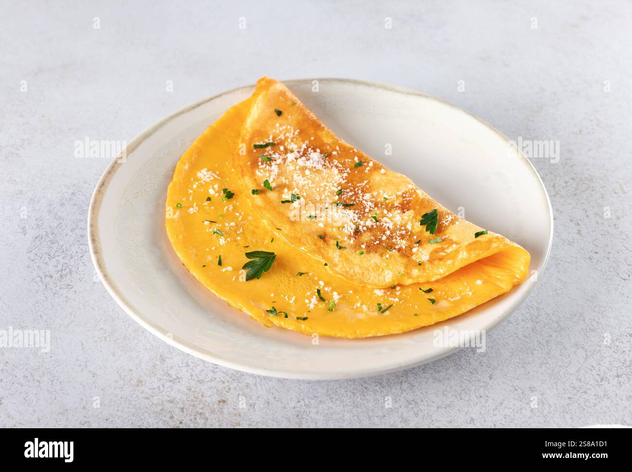 Omelette aux oeufs nature avec parmesan et persil sur fond gris. Banque D'Images