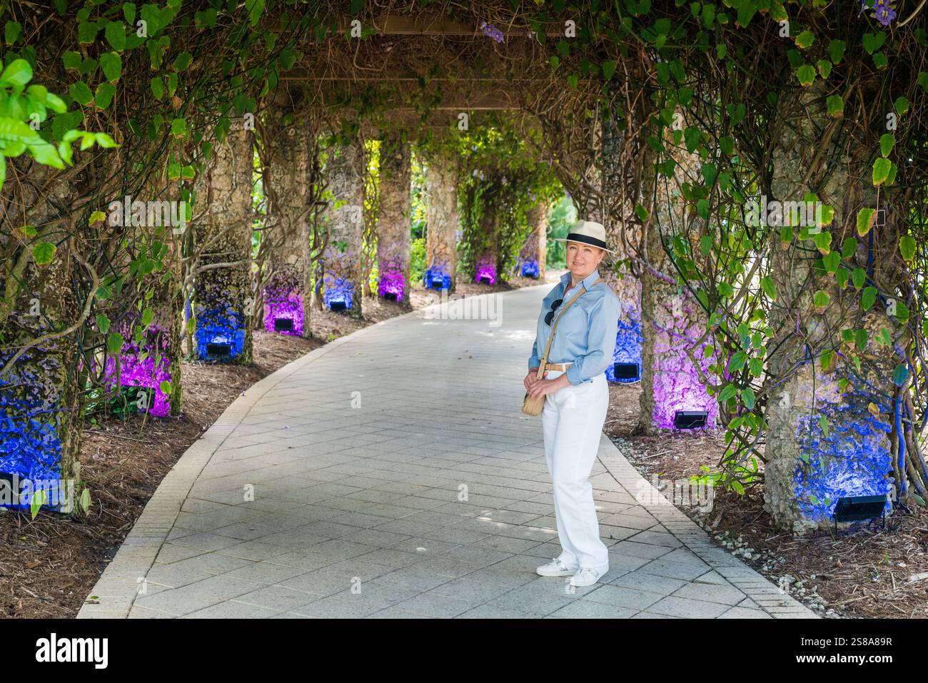 а belle femme dans l'allée couverte dans un jardin en Floride Banque D'Images
