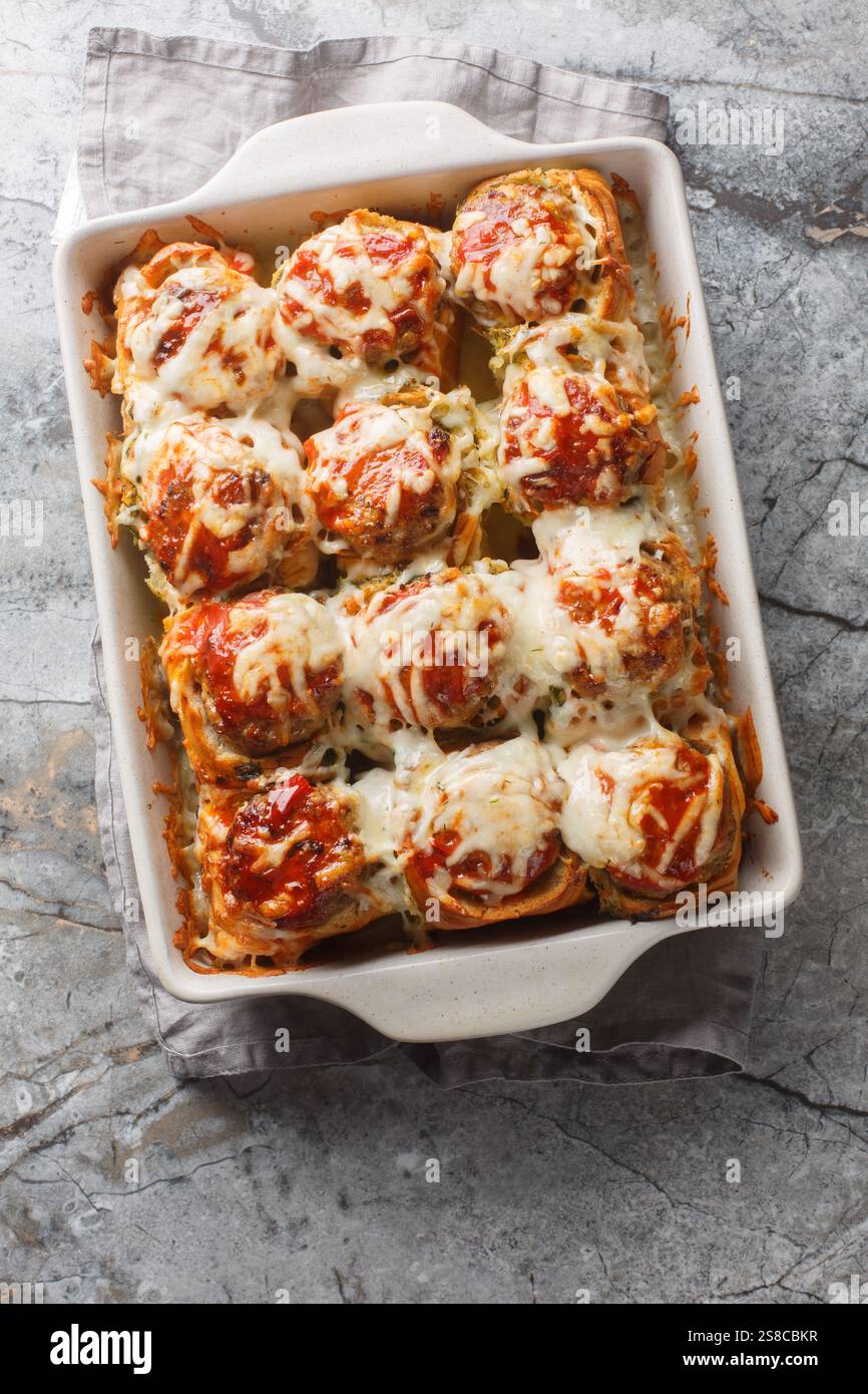 Hors-d'œuvre chaud paniers à l'ail farcis de boulettes de viande, recouverts de sauce tomate et de fromage râpé gros plan dans un plat allant au four sur une table. Vie supérieure verticale Banque D'Images