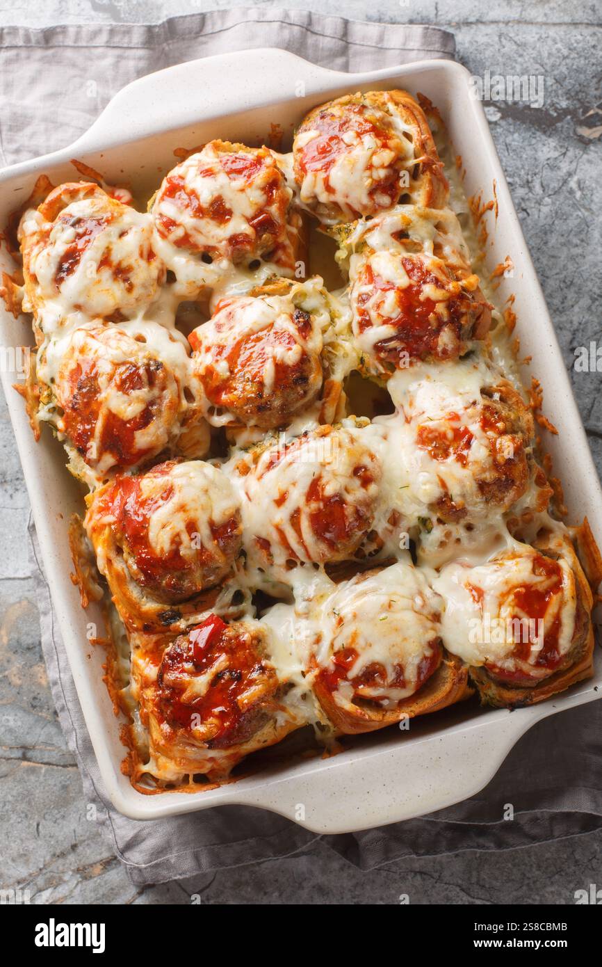 Boulettes de pain à l'ail farcies de boulettes de viande recouvertes de gros plan de fromage sur le plat de cuisson sur la table. Vue de dessus verticale Banque D'Images