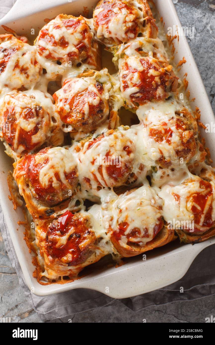 Pain à l'ail les bombes Meatball sont des petits pains farcis avec une boulette de viande et une sauce, puis recouverts de gros plan de fromage sur le plat de cuisson sur la table. Verti Banque D'Images