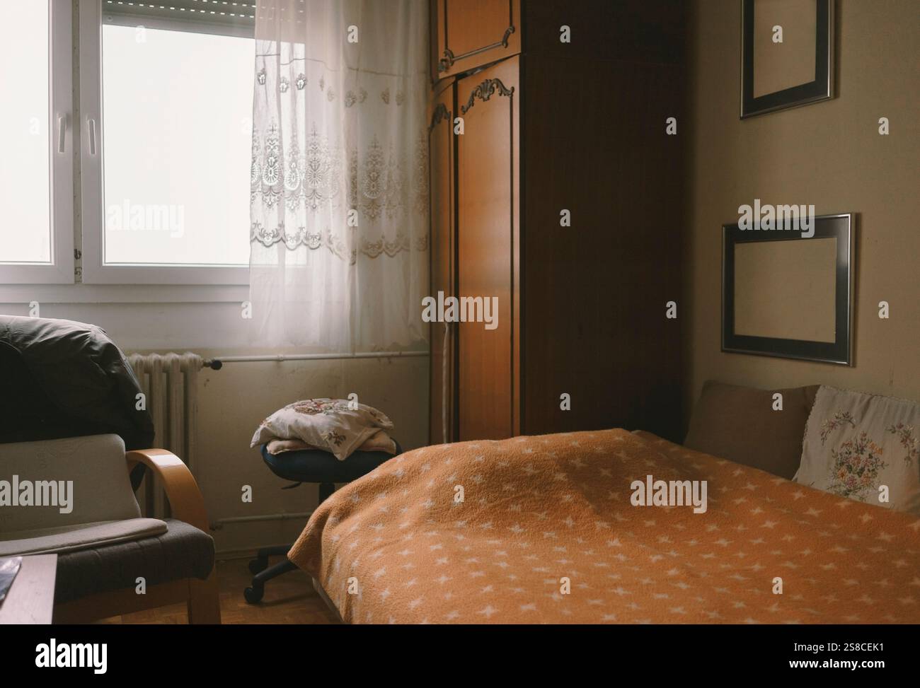 Intérieur d'une chambre ancienne, un lit, ancienne armoire, couverture et cadres vides. C'est le jour, c'est nostalgique. Banque D'Images Intérieur d'une chambre ancienne, un lit, ancienne armoire, couverture et cadres vides. C'est le jour, c'est nostalgique. Banque D'Images