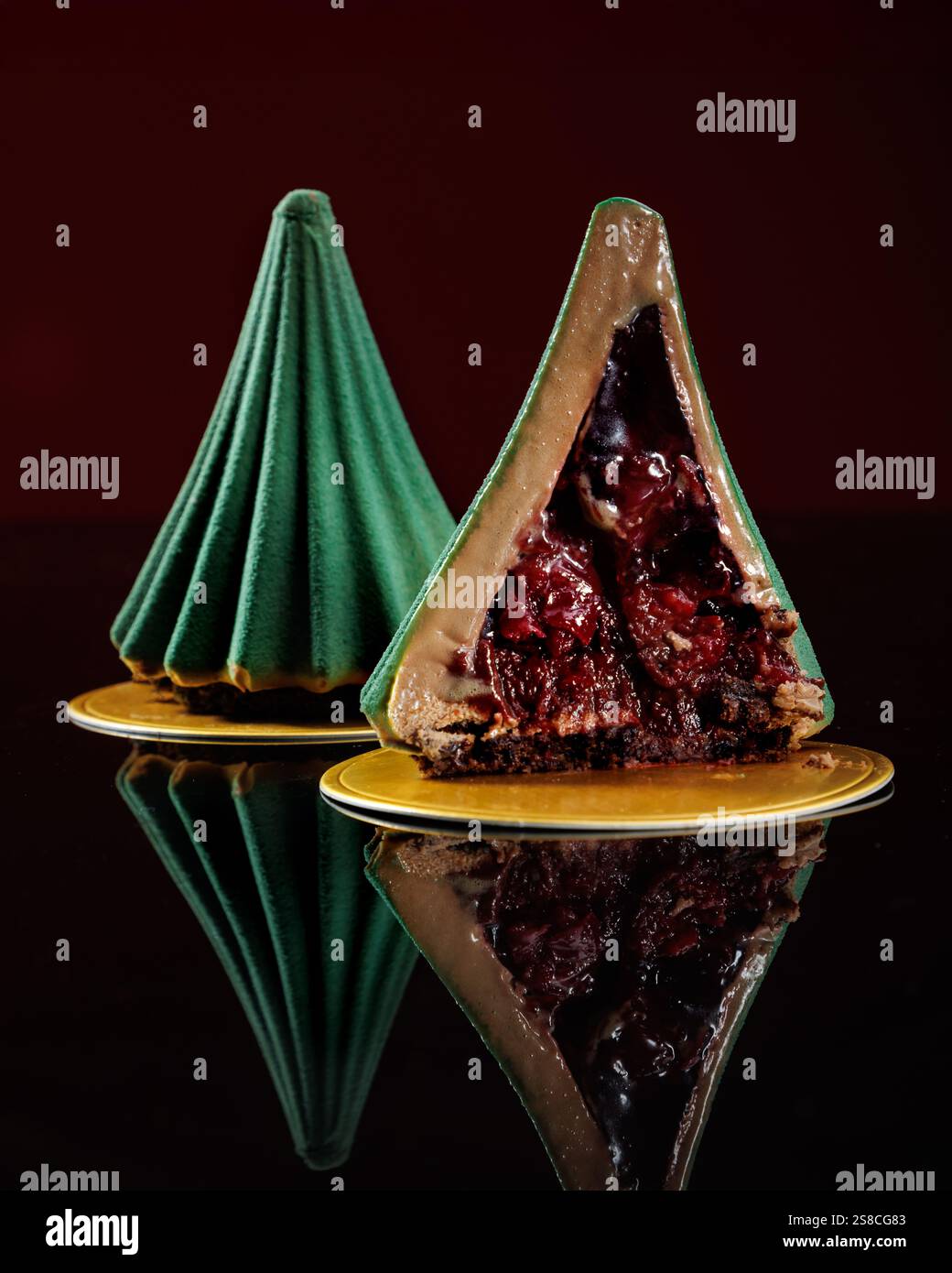 Arbres de Noël verts en forme de gâteaux sur fond rouge. Gâteaux mousse au chocolat et aux cerises. Desserts festifs Banque D'Images