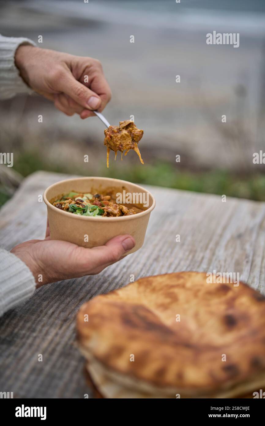 Soupe de poulet épicée d'hiver et pains plats cuits sur le feu au café Hidden Hut à Porthcurnick Beach, Cornwall, Royaume-Uni Banque D'Images