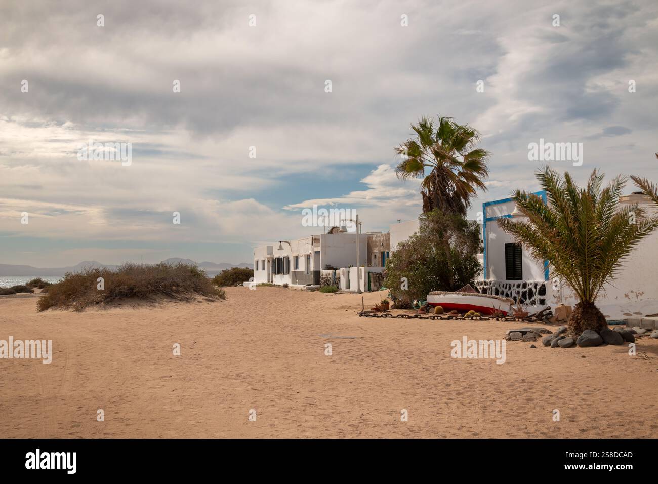 Village avec façade blanche traditionnelle des maisons. Pas de circulation, toutes les rues couvertes de sable. Verdure tropicale. Ciel nuageux en hiver. Caleta Banque D'Images
